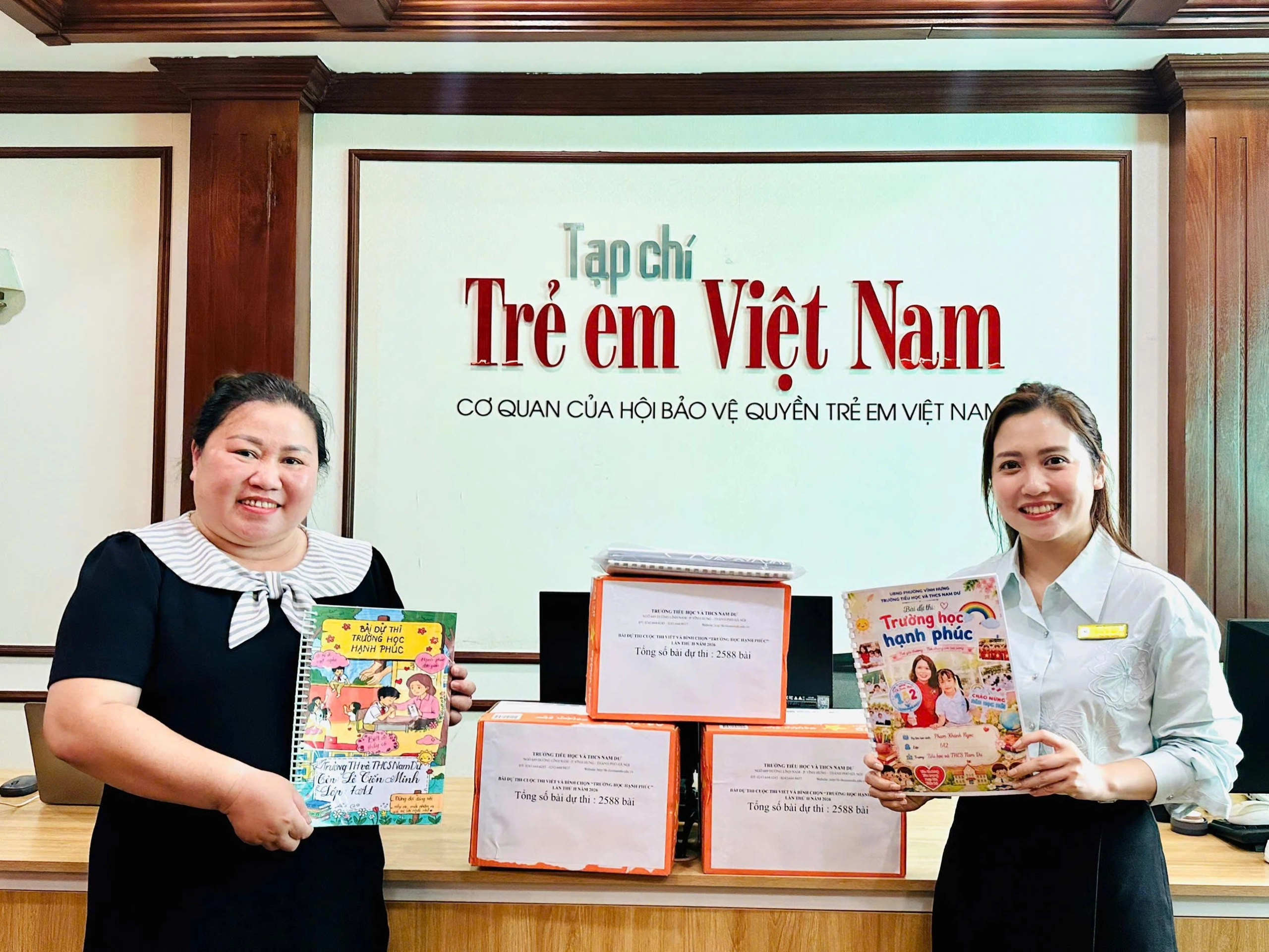 Cô Trần Lệ Khanh - Hiệu trưởng và cô Dương Thị Vân Anh - Phó Hiệu trưởng Trường Tiểu học và THCS Nam Dư (phường Vĩnh Hưng, Hà Nội) trực tiếp mang 2.588 bài dự thi đến Ban Tổ chức cuộc thi “Viết và bình chọn trường học hạnh phúc 2026”. trường nam dư